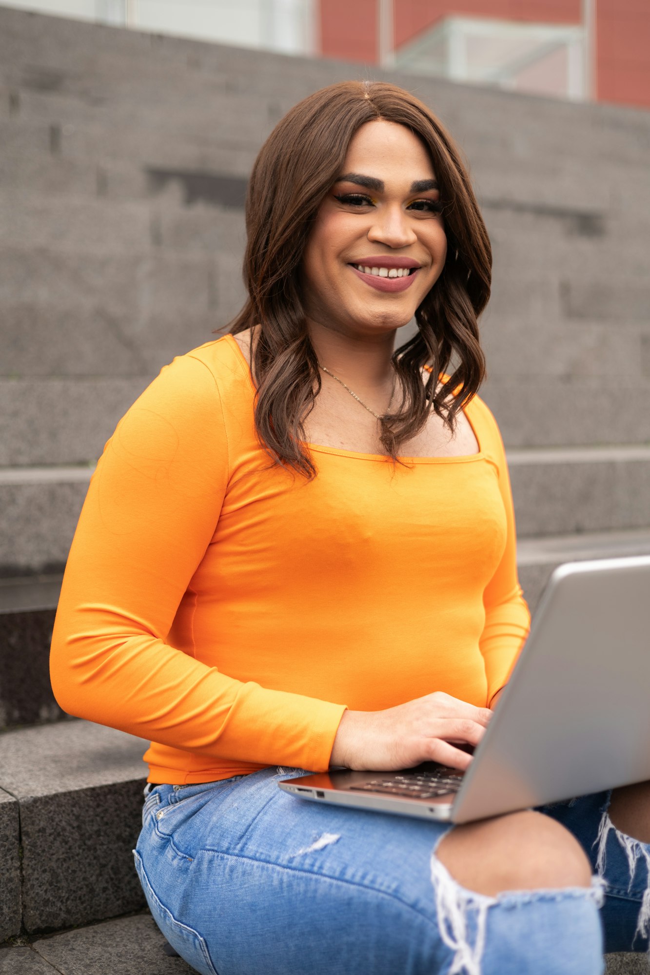 Close-up portrait of trans latin woman using laptop in campus stairs. Trans inclusion concept.